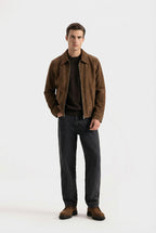 Man wearing a brown jacket and dark pants on a white background